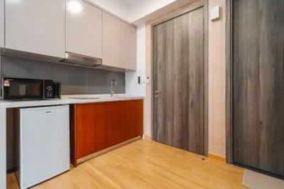 a kitchen with a white refrigerator and a wooden door at Woody Studio Agile Bukit Bintang by RumaBnB in Kuala Lumpur