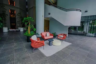a lobby with red chairs and tables in a building at The Atrium at Jalan Ampang by OKBnB - Cozy 2Bedroom ,3 mins to Foreign Embassies in Kuala Lumpur
