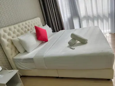 a large white bed with two red pillows at STAR Residences Popular By KLCC in Kuala Lumpur