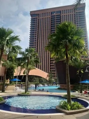 a pool in front of a tall building with palm trees at Eastern Suites Times Square KL in Kuala Lumpur