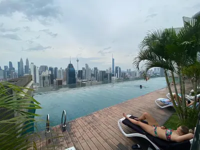 a woman laying in chairs by a pool with a city skyline at Skypool KL Free Infinity Pool over Kuala Lumpur in Kuala Lumpur