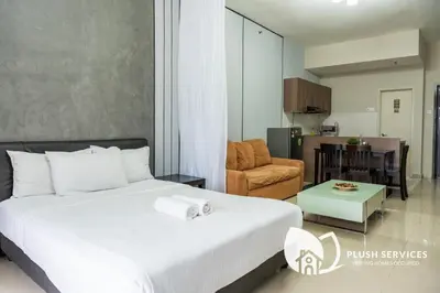 a bedroom with a bed and a living room at Windsor Tower Sri Hartamas by Plush in Kuala Lumpur