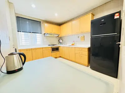 a kitchen with a black refrigerator and wooden cabinets at Soha Homestay in Kuala Lumpur