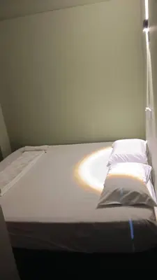 a bed in a room with a white sheet and pillow at Health Homestay KL in Kuala Lumpur
