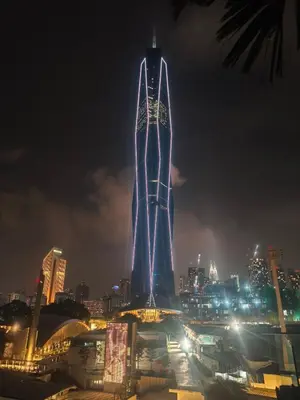 a tall building lit up with blue lights at night at 8Pax Green View next to KL118 ChinaTown n Train Station in Kuala Lumpur