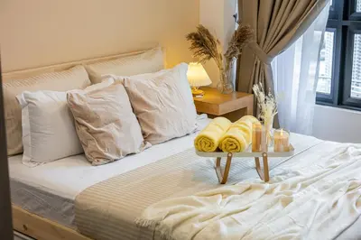 a bed with white pillows and a tray with towels on it at TRX View Muji Room 5 min to Bukit Bintang at Agile in Kuala Lumpur