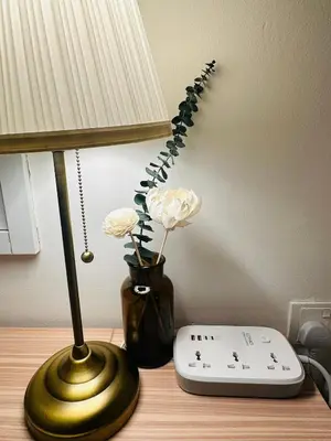 a lamp and a vase with flowers on a table at The Establishment LOFT Bangsar KL Sentral by \u54c1\u5c4b PINWU Shortstay in Kuala Lumpur
