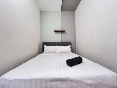 a white bed with a black bag sitting on it at Arte Mont Kiara By Comfortstay in Kuala Lumpur