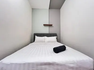 a white bed with a black pillow on it at Arte Mont Kiara By Comfortstay in Kuala Lumpur