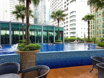 a pool with palm trees and people in a building at Vortex Suites KLCC By Farysha in Kuala Lumpur