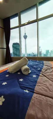 a bed in a room with a view of a tower at Sky Suites KLCC Apartment by Family Room Stay in Kuala Lumpur