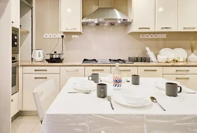 a white kitchen with a table with plates and cups at Fahrenheit #185 Kuala Lumpur Bukit Bintang in Kuala Lumpur