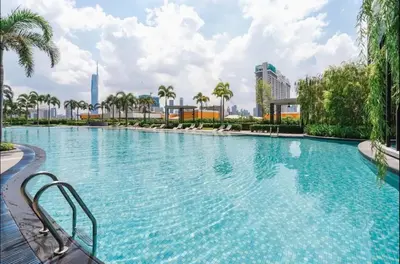 a large swimming pool with palm trees in a city at trion kl one bedroom studio in Kuala Lumpur