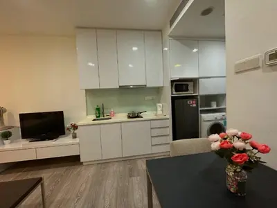 a kitchen with white cabinets and a vase of flowers on a table at 1Bukit ceylon view 118 in Kuala Lumpur
