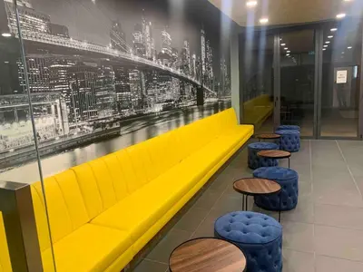 a yellow couch in a restaurant with tables and stools at Private Room Queen Size KLCC in Kuala Lumpur
