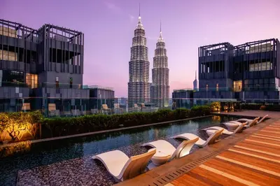 a pool with chairs and the petronas towers at Star Deluxe Suites KLCC by WSD in Kuala Lumpur
