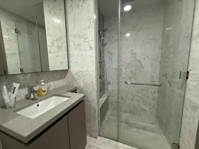 a bathroom with a sink and a shower with a glass door at Eaton Premier Suite KLCC in Kuala Lumpur