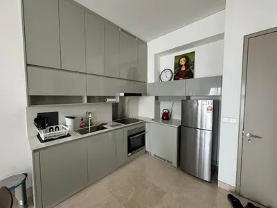 a kitchen with white cabinets and a stainless steel refrigerator at Lucentia Residences in Kuala Lumpur
