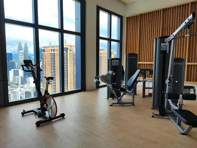 a gym with bikes and exercise equipment in a room with windows at Lucentia Residences in Kuala Lumpur