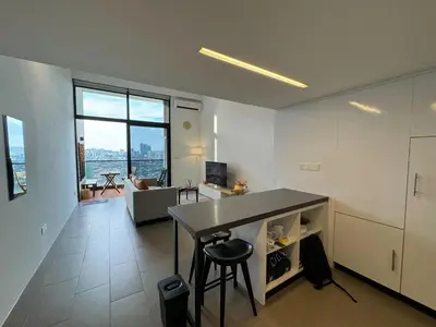 a kitchen and living room with a counter and a table at Cozy Fall Suite at EST Bangsar With Garden Scenery in Kuala Lumpur