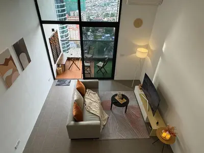 a living room with a couch and a large window at Cozy Fall Suite at EST Bangsar With Garden Scenery in Kuala Lumpur