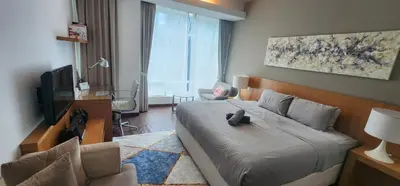 a bedroom with a bed and a television and a chair at COZY SUPER KING BED STUDIO walking to PETRONAS KLCC by Zen Glo in Kuala Lumpur