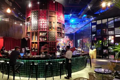 a bar in a restaurant with people standing around it at COZY SUPER KING BED STUDIO walking to PETRONAS KLCC by Zen Glo in Kuala Lumpur