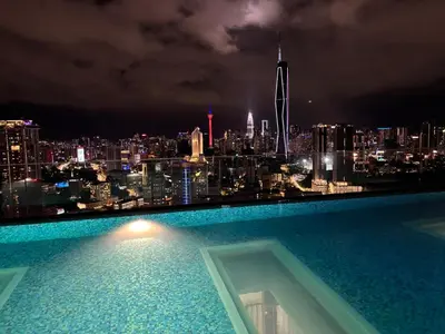a swimming pool with a view of a city at night at Riveria City in Kuala Lumpur
