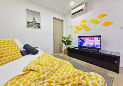 a bedroom with a tv and a bed with a yellow blanket at Bukit Bintang Fairlane Residence #199 KL TRX Pavilion in Kuala Lumpur