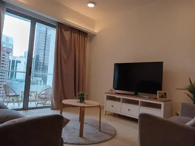 a living room with a flat screen tv and a table at Luxury Balcony Suites- Homestay in Kuala Lumpur