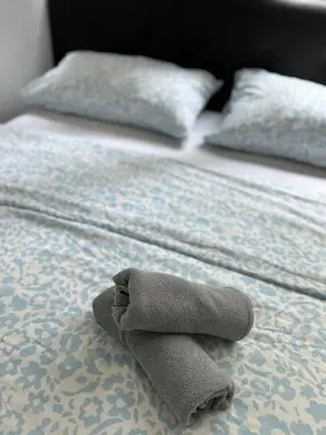 a towel laying on a bed with two pillows at Stay at Regalia KLCC View Sky Pool in Kuala Lumpur