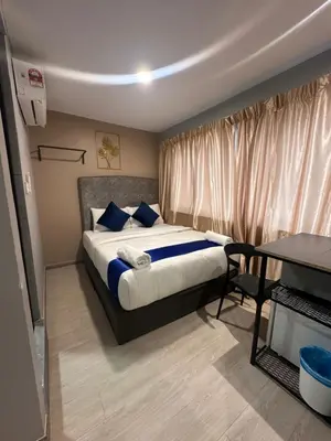 a bedroom with a bed with blue pillows and a table at SS Grey inn Bukit Bintang in Kuala Lumpur