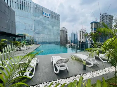 a pool on the roof of a building with chairs at Dorsett Residence Service Suites at Kuala Lumpur in Kuala Lumpur