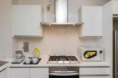a white kitchen with a stove and a microwave at Publika Mont Kiara City View Suite - 8KM to KLCC in Kuala Lumpur