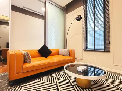 a living room with an orange couch and a table at Royce Residences KLCC by WSD in Kuala Lumpur