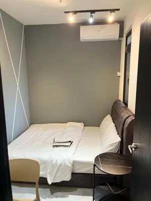 a bed in a small room with a leather couch at Neu Suites 2 Room Home Stay in Kuala Lumpur