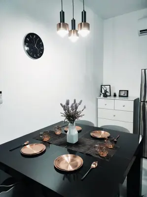 a dining room table with plates and a clock on the wall at Neu Suites 2 Bedroom Family Suites in Kuala Lumpur