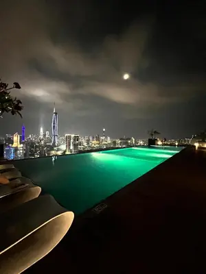 a pool with a view of a city at night at Reveria city KL in Kuala Lumpur