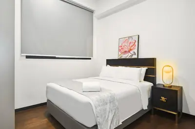 a white bedroom with a bed and a tv at Atelier 118 Chinatown in Kuala Lumpur