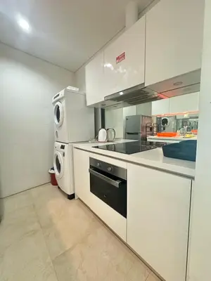 a kitchen with white cabinets and a washer and dryer at Vortex Suites KLCC by Angel in Kuala Lumpur