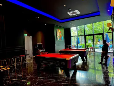 a man standing in a room with two pool tables at The KLCC At Star SKY Pools in Kuala Lumpur