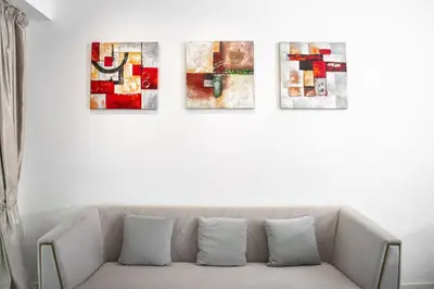 a living room with a couch with four pictures on the wall at MyHabitat Residences in Kuala Lumpur
