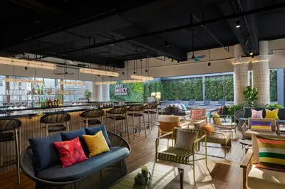 a restaurant with a bar with chairs and tables at Moxy Kuala Lumpur Chinatown in Kuala Lumpur