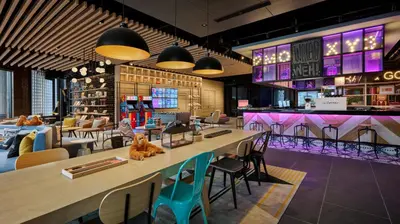 a restaurant with a bar with tables and chairs at Moxy Kuala Lumpur Chinatown in Kuala Lumpur