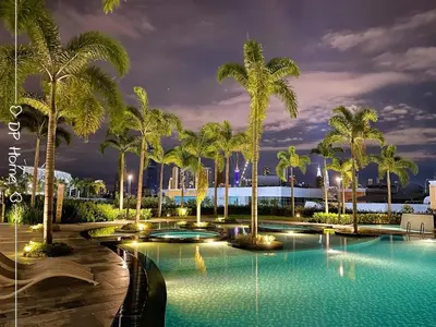 a pool with palm trees at night at 5 STAR Homestay 3R3B KL View Trion TRX Velocity in Kuala Lumpur