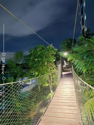 a suspension bridge over a walkway with trees and a building at 5 STAR Homestay 3R3B KL View Trion TRX Velocity in Kuala Lumpur