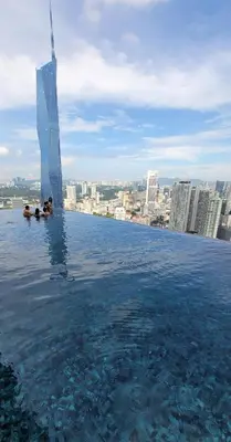 a infinity pool with people swimming in the water at The BirdsEye View facing KLCC with Gorgeous pools in Kuala Lumpur