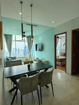 a dining room with a table and chairs and a living room at Sky Suites KLCC host by REST Corner Suites in Kuala Lumpur