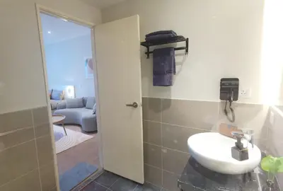 a bathroom with a white sink and a living room at Weekly Monthly Stay - Bangsar Trade Centre Curvena in Kuala Lumpur