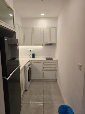 a small kitchen with white cabinets and a washer at AXON Bukit Bintang Suites KL in Kuala Lumpur